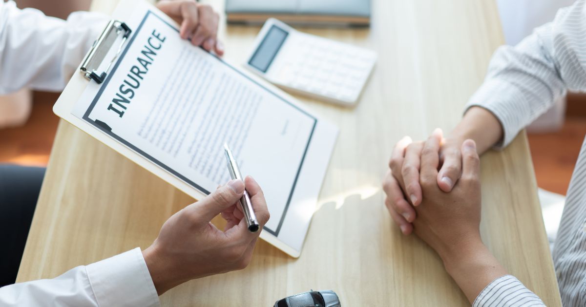 Agent explaining insurance services details with policy document and pen during client consultation